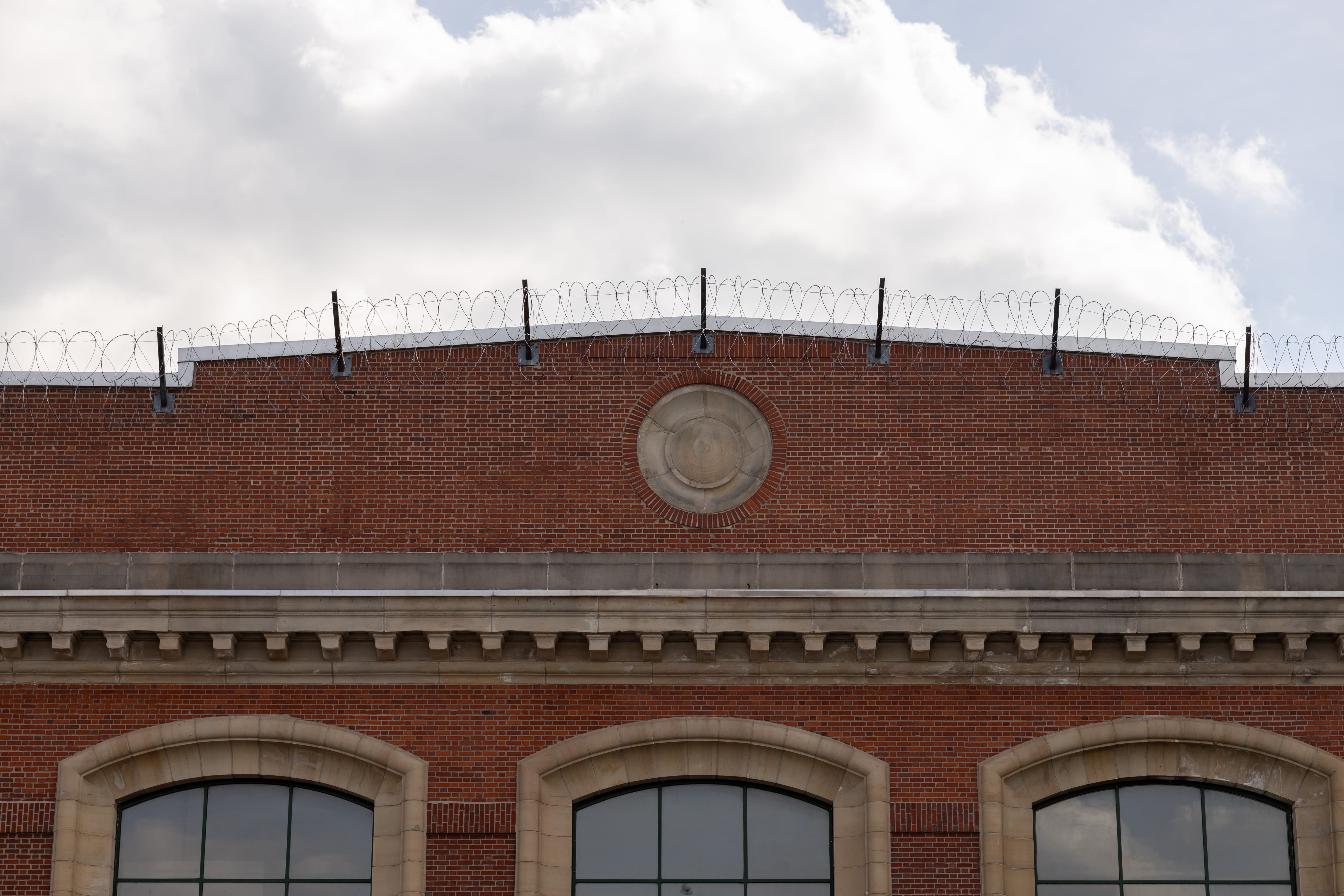 Initial view of the main entrance at London Correctional Institution featuring a large brick building with razor wire on the roof.