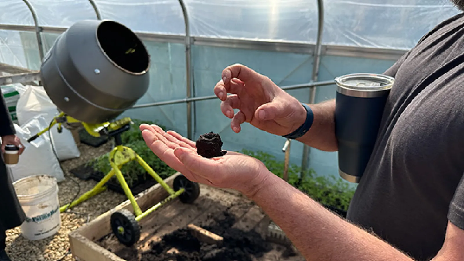 NECIC Urban Farm Manager Daniel Neef holds a small clump of soil while explaining some of the science behind the Urban Farm's soil processes.