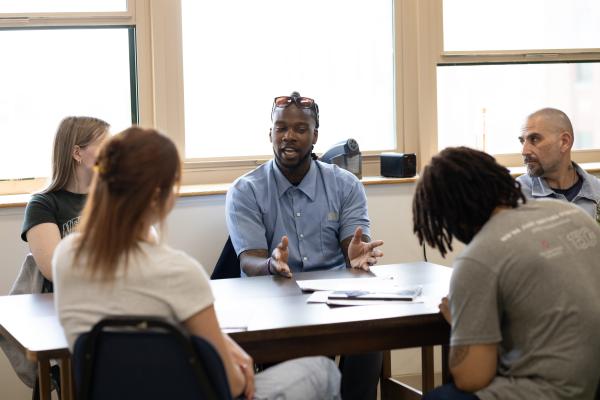 5 students, 3 campus-based and 2 incarcerated, sit around a table for a class discussion in Dr. Terrance Hinton's Spring 2024 Corrections class held at London Correctional Institution.