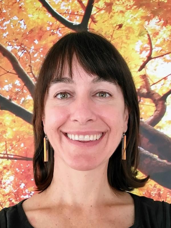 Alia Dietsch smiling woman with brown hair and gold earrings