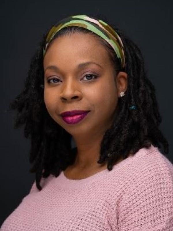 Woman wearing green & brown headband, red lipstick & pink sweater