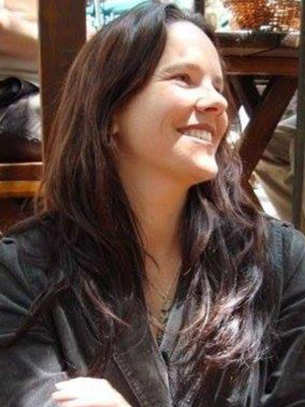 Smiling woman with long dark brown hair wearing a dark shirt.