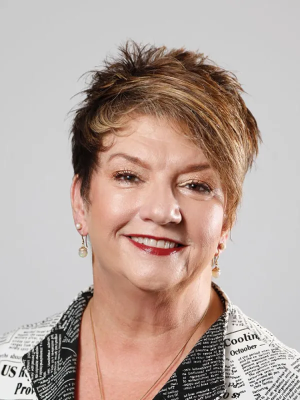 Smiling white woman with short brown hair, red lipstick, and a white blouse.