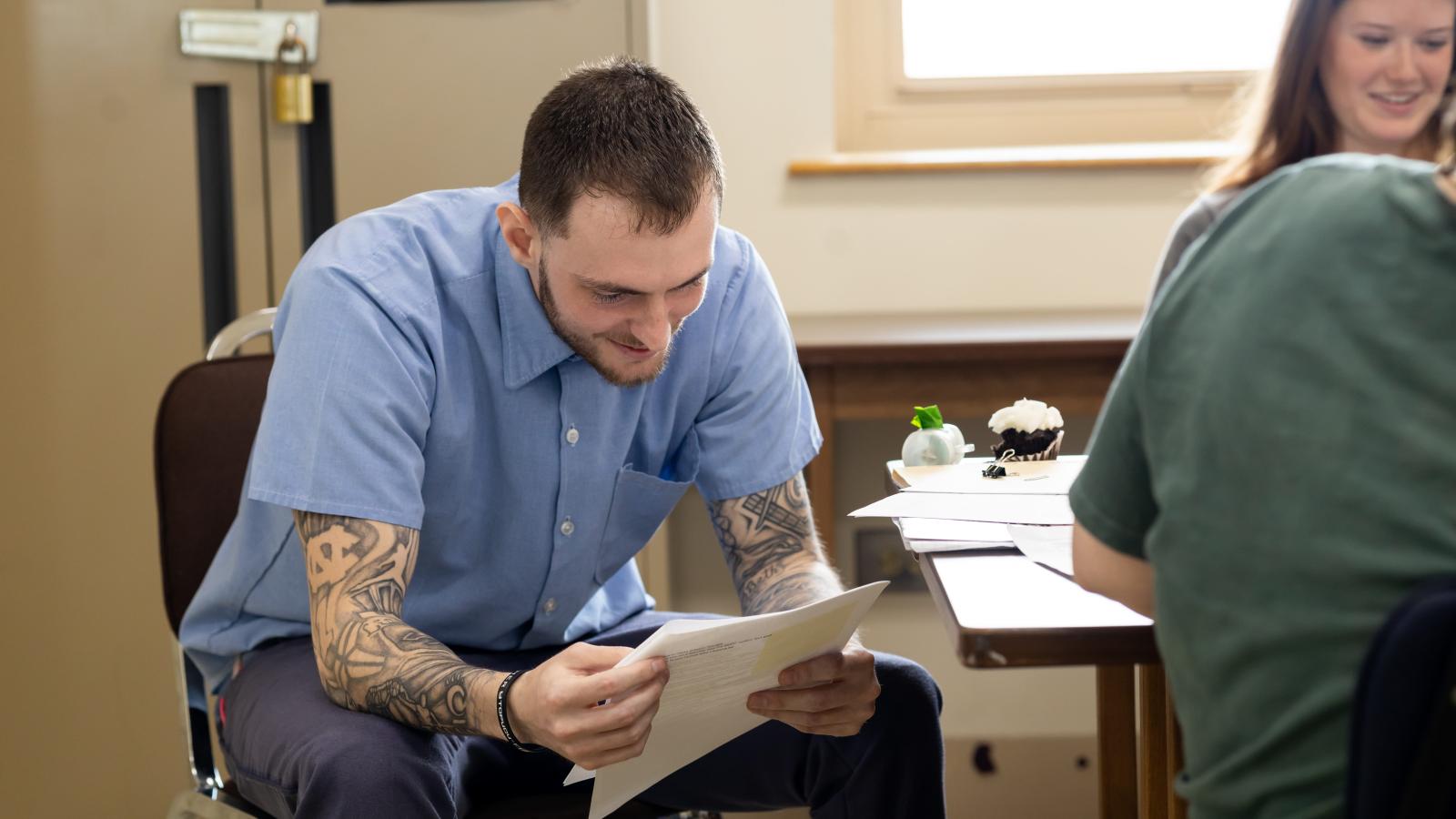 Incarcerated student Justin smiles while reading one of his peer's reflection essays and enjoying the celebratory activities on the final day of Dr. Terrance Hinton's Corrections class held at London Correctional Institution in Spring 2024.