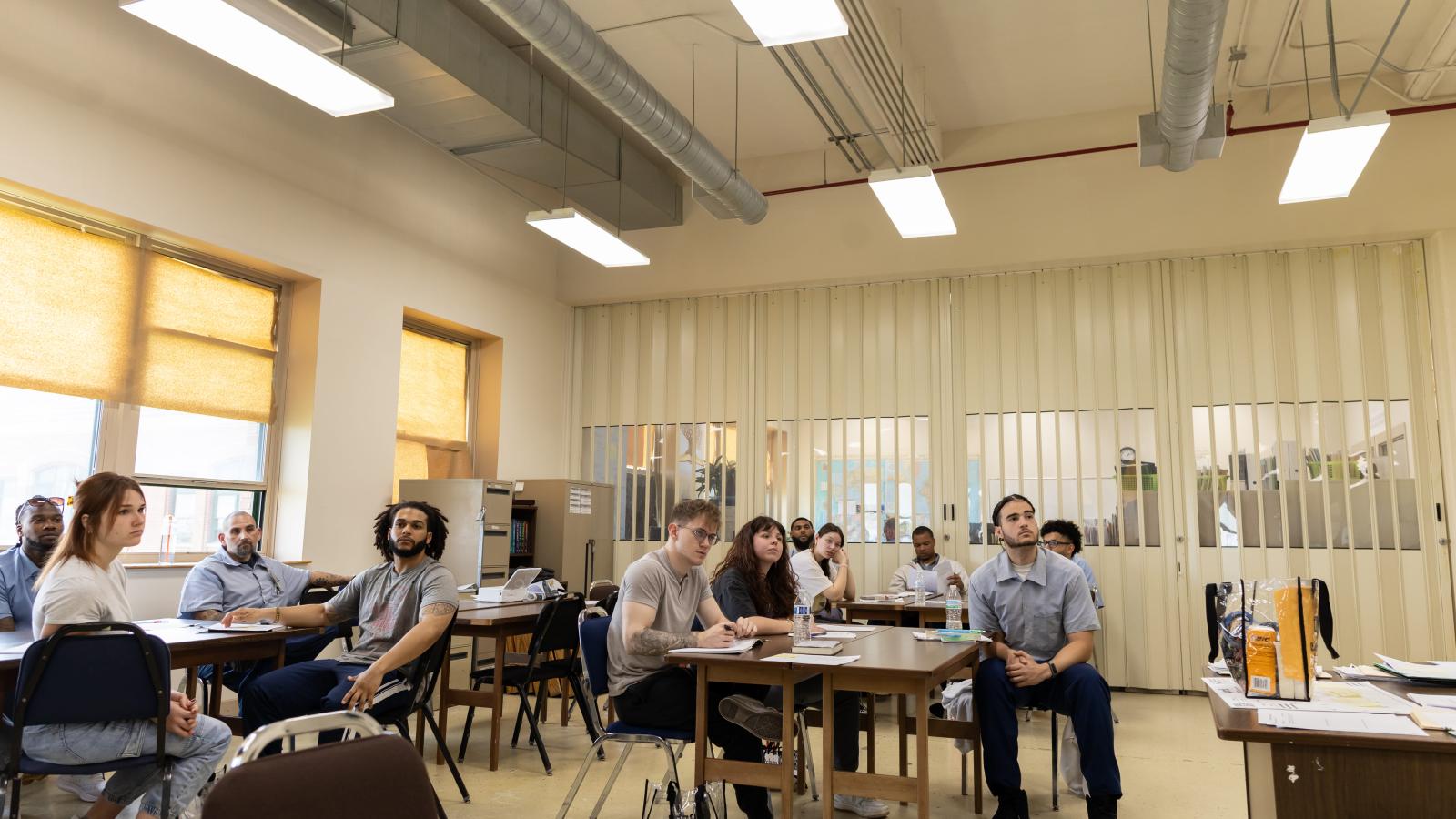 6 incarcerated students and 5 campus-based students look to the front of the room while listening to reflections from their peers on the final day of Dr. Terrance Hinton's Corrections class held at London Correctional Institution in Spring 2024.